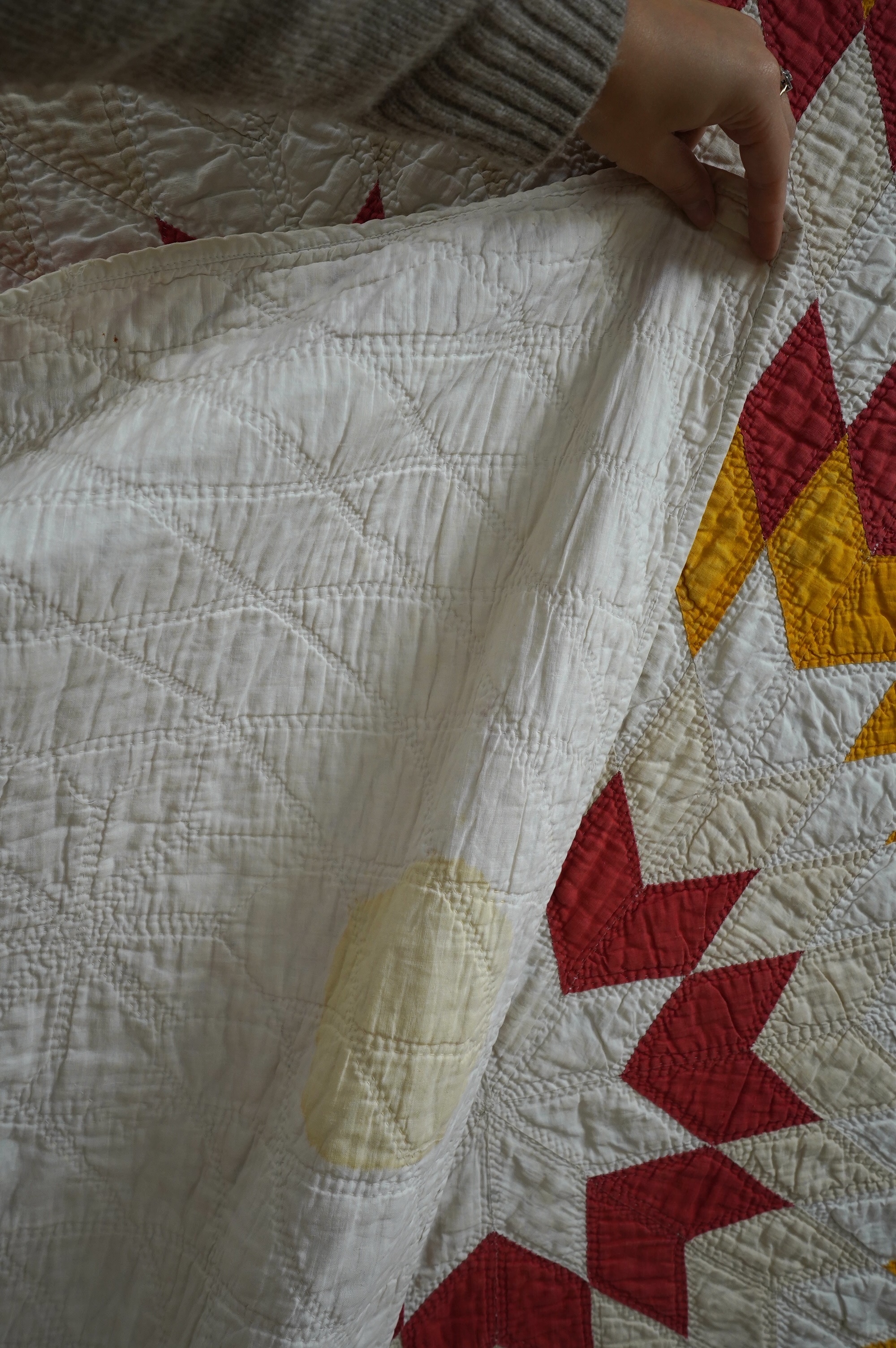 A late 19th century / early 20th century American ‘Star of Bethlehem’ quilt, worked on a plain light cream ground with red and yellow and beige patchworks forming a large double line star with a simple single red inner l